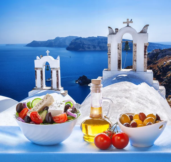 Greek salad against church in Oia village, Santorini island in Greece — Stock Photo, Image