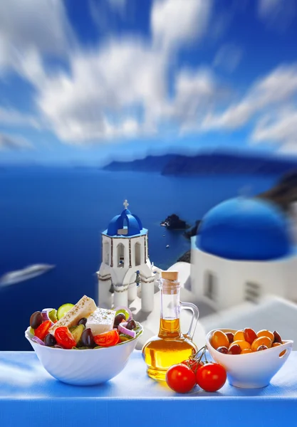 Greek salad against church in Oia village, Santorini island in Greece — Stock Photo, Image