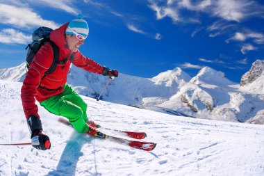 Yokuş aşağı mavi gökyüzü karşı yüksek dağlarda kayak kayakçı