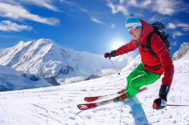 Yokuş aşağı mavi gökyüzü karşı yüksek dağlarda kayak kayakçı