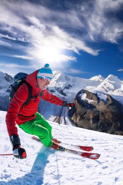 Yokuş aşağı mavi gökyüzü karşı yüksek dağlarda kayak kayakçı