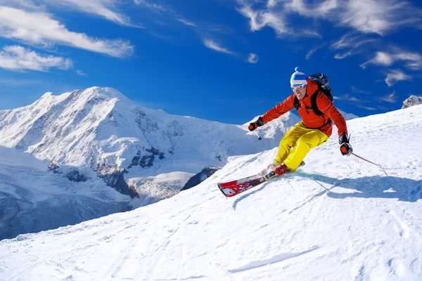 Skiër skiën afdaling in hoge bergen tegen blauwe hemel — Stockfoto