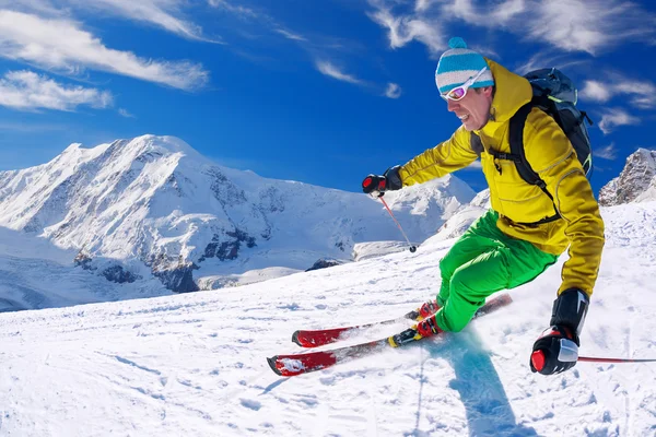Narciarz narty zjazdowe w wysokich górach przeciw błękitne niebo — Zdjęcie stockowe