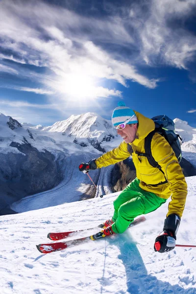 Skiër skiën afdaling in hoge bergen tegen blauwe hemel — Stockfoto