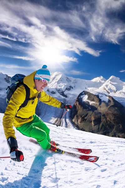 Skier skiing downhill in high mountains against blue sky — Stock Photo, Image