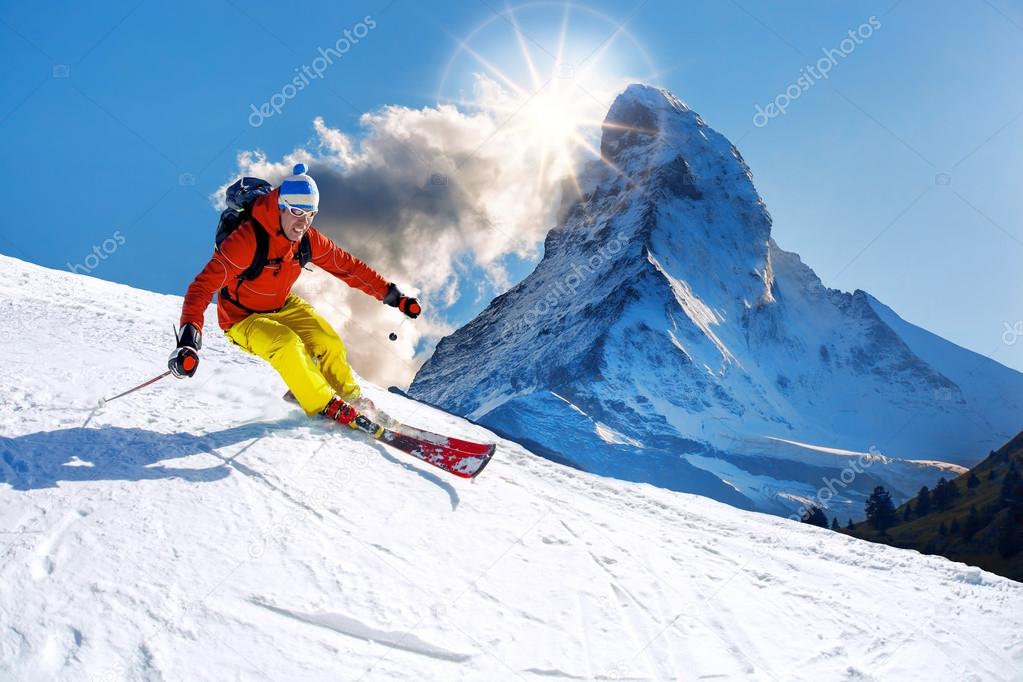 Skier skiing downhill against Matterhorn peak in Switzerland