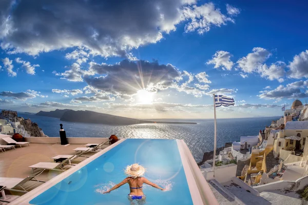 Mulher na piscina contra o pôr do sol na ilha de Santorini, na Grécia — Fotografia de Stock