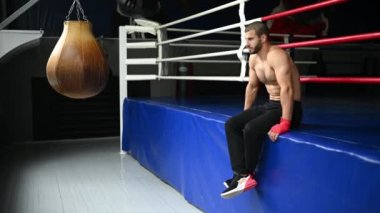Dövüşçü Kum Torbasıyla Tekme Antrenmanı yapıyor. Koyu arkaplanda tekme, kum torbası. Spor salonunda siyah kum torbası tartılır.