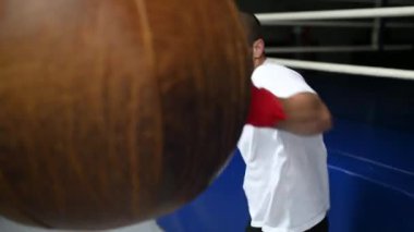 Dövüşçü Kum Torbasıyla Tekme Antrenmanı yapıyor. Koyu arkaplanda tekme, kum torbası. Spor salonunda siyah kum torbası tartılır.