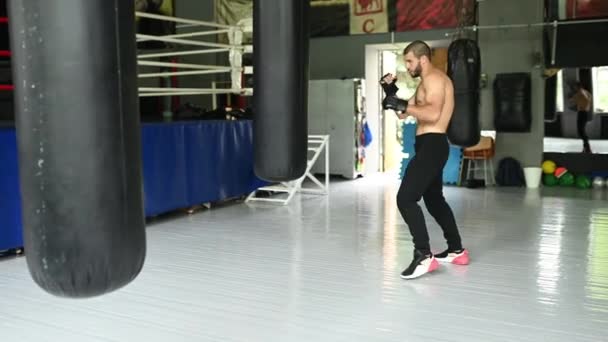 Combatiente practicando algunas patadas con saco de boxeo. Patada, saco de boxeo sobre fondo oscuro. saco de boxeo negro pesa en el gimnasio — Vídeo de stock