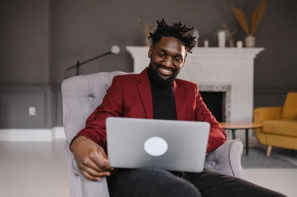 O homem preto em um terno comunica-se por videoconferência. Homem de negócios afro-americano em casa — Fotografia de Stock