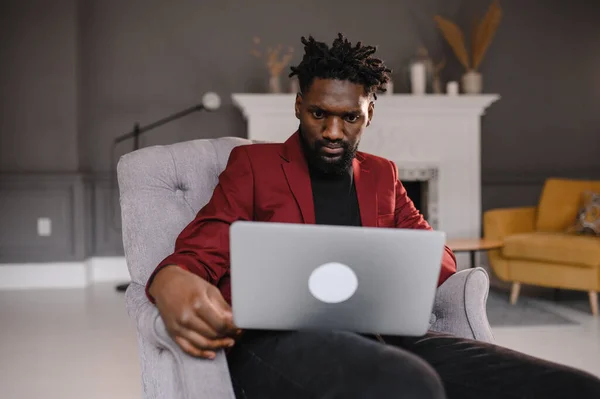 O homem preto em um terno comunica-se por videoconferência. Homem de negócios afro-americano em casa — Fotografia de Stock