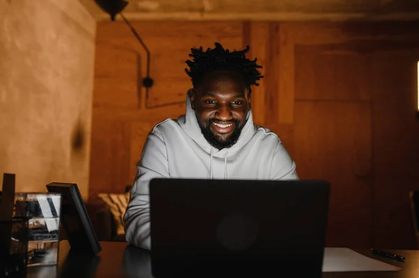 Um homem negro trabalha num computador portátil perto do seu rosto. videoconferências — Fotografia de Stock