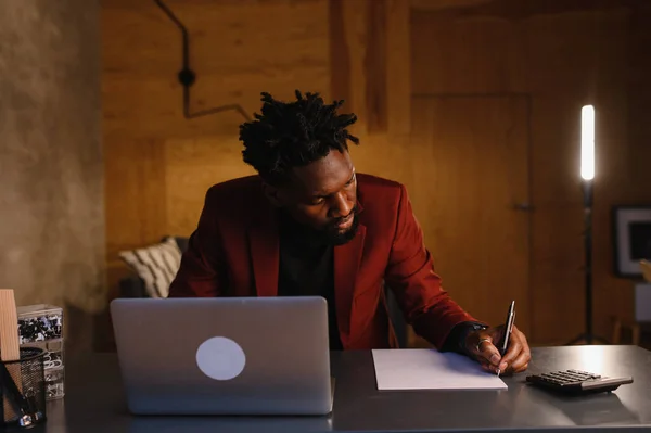 Homem de negócios preto trabalhando no laptop e tomar notas — Fotografia de Stock