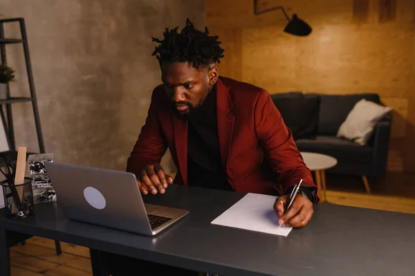Homem de negócios preto trabalhando no laptop e tomar notas — Fotografia de Stock