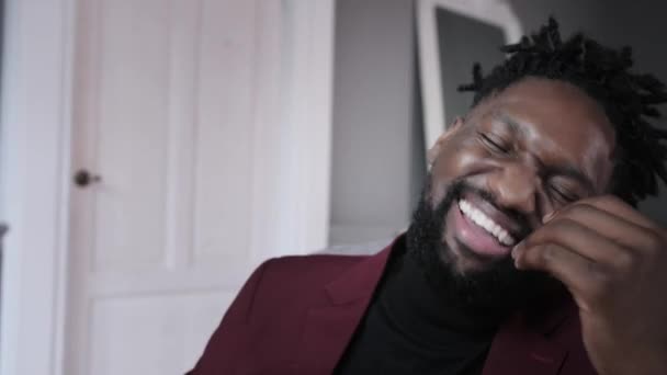 Souriant beau jeune homme afro-américain assis, regardant l'écran d'ordinateur. Homme biracial millénaire concentré travaillant sur un projet dans un bureau moderne ou étudiant en ligne à la maison. — Video