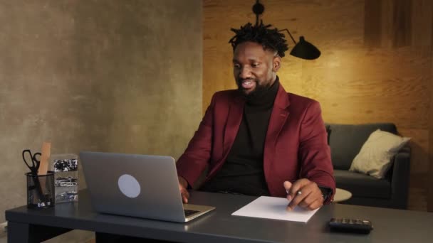 Czarny biznes człowiek pracuje na laptopie i robi notatki — Wideo stockowe