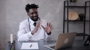  Klasik takım elbiseli yakışıklı Afro-Amerikan iş adamı ofiste çalışırken dizüstü bilgisayar kullanıyor ve gülümsüyor.