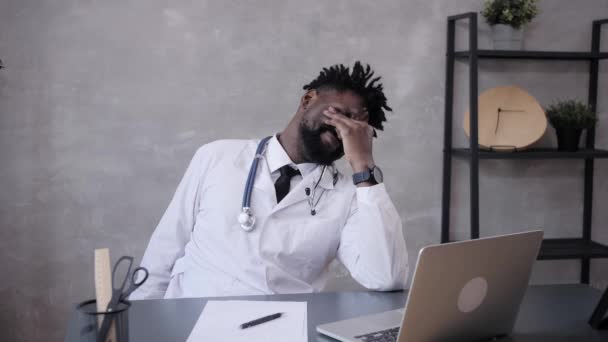 Забавно працюючи лікарем-афроамериканцем, який засинає за робочим столом. Працівники, які сплять на робочому місці біля ноутбука, відчувають себе перепрацьованими. — стокове відео