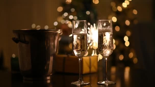Ett två glas mousserande vin på nyår. Glas av champagne på julafton med suddiga bengaliska ljus bakgrund. Begreppet nyår och jul — Stockvideo