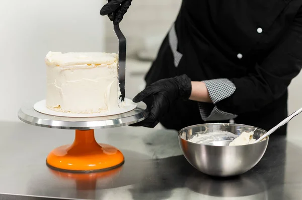 woman pastry chef in uniform prepares cake