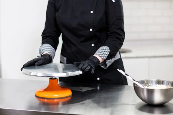 woman pastry chef in uniform prepares cake
