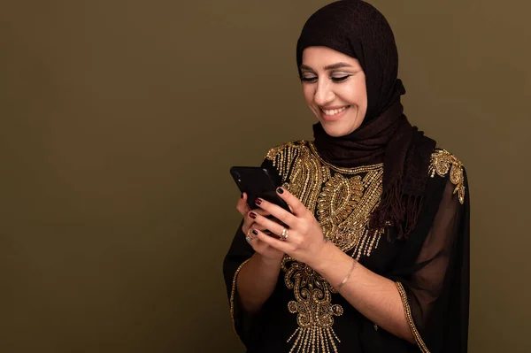 Donna musulmana che ride tenendo lo smartphone in mano e scattando selfie — Foto Stock