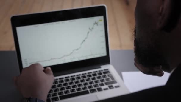 De jonge zakenman analyseert de financiële grafiek op een laptop in het kantoor. beurshandel — Stockvideo