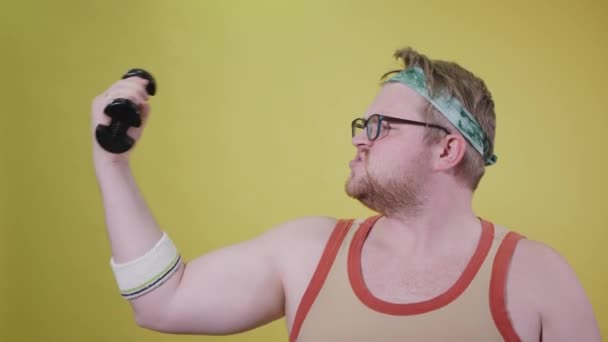 Muž s nadváhou dělá biceps jednou rukou, jí sušenku druhou. tlustý vtipálek — Stock video