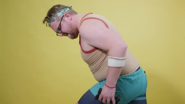Człowiek z nadwagą uprawia sport na żółtym tle. Zabawny grubas. — Wideo stockowe
