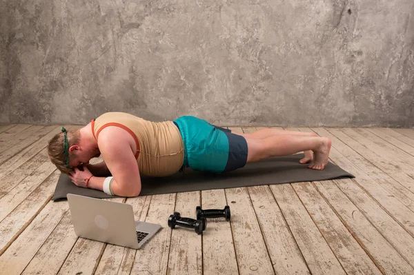 Übergewichtige beim Sport, Dehnübungen auf der Yogamatte, Fitnessvideos online auf dem Laptop zu Hause. Yoga-Übungen online mit Laptop — Stockfoto