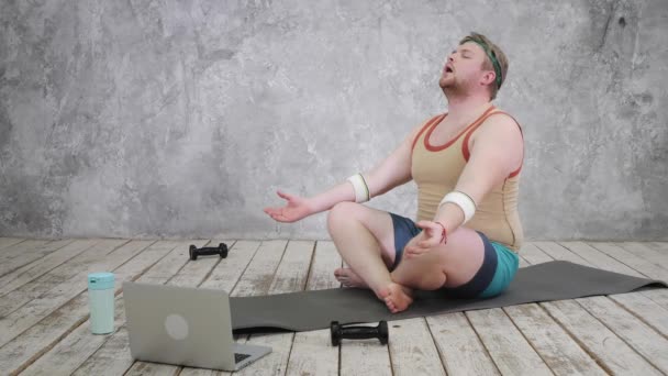 Nadváha muž cvičení, dělá strečink cvičení na podložce jógy, sledování fitness videa on-line na notebooku doma. jóga cvičení online s notebookem — Stock video