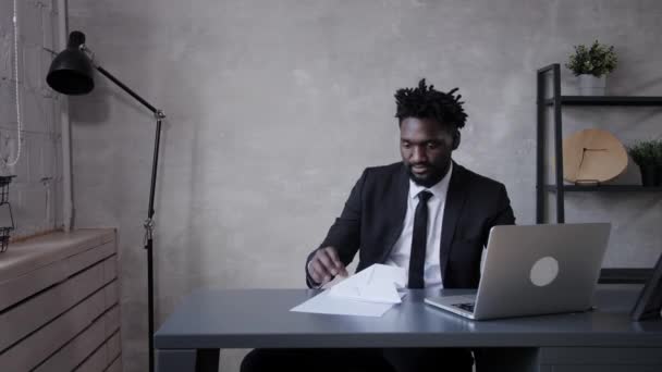Uomo d'affari afro-americano fa aereo di carta e lo lancia in ufficio — Video Stock