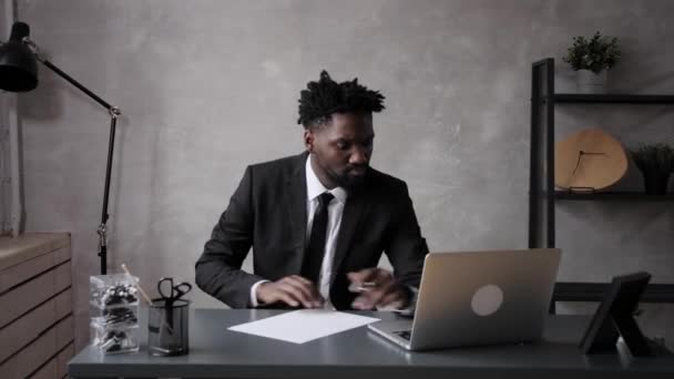 Бизнесмен афроамериканец делает заметку на листе бумаги, что что-то не получается, выбрасывает лист бумаги и расстраивается — стоковое видео