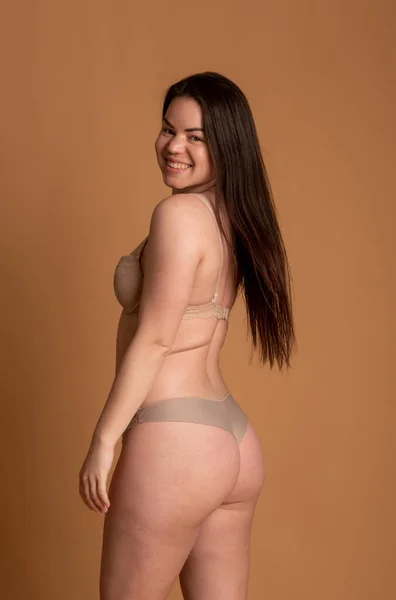 Schöne übergewichtige Frau im beigen Badeanzug auf rosa Hintergrund — Stockfoto
