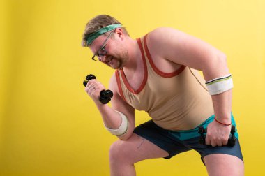 Sarı arka planda kaslarını kasan komik şişman adam.