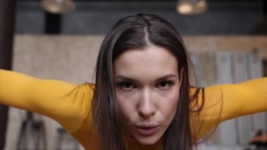 Sarı spor kıyafetli genç ve güzel bir kız şınav çekiyor. Kapat. 