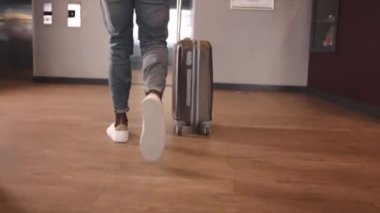 Siyah işadamı asansöre doğru yürüyor ve apartman koridorundaki panelde asansör düğmesine basıyor. Siyah adam asansöre biniyor ve kapı kapanıyor.
