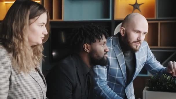Genç geliştiricilerden oluşan bir ekip dizüstü bilgisayardaki projeyi tartışıyorlar. çok ırklı takım — Stok video