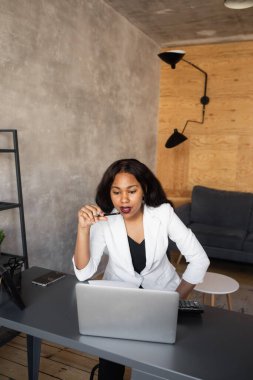 Modern bir ofiste oturan oldukça neşeli bir siyahi iş kadınının portresi. Pozitif düşünce konsepti