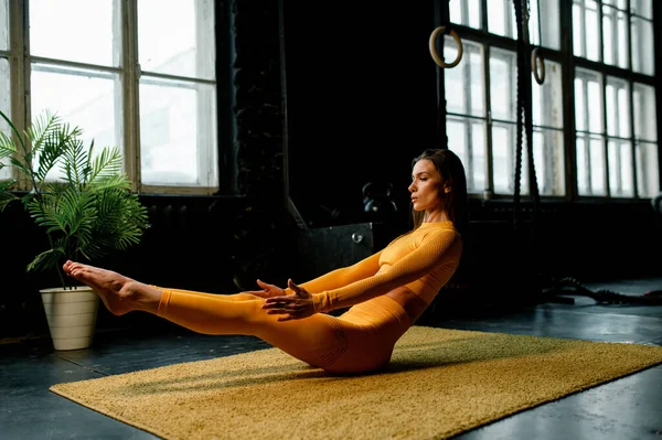 Sarı spor kıyafetli güzel kız yoga yapıyor, doğru nefes alıyor. Modern spor salonu — Stok fotoğraf