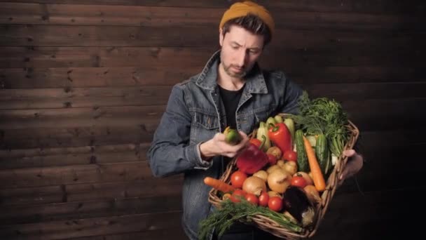 Giovane agricoltore tiene un cesto di vimini con verdure biologiche fresche. piccola impresa. Studio girato — Video Stock