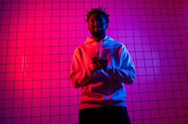 Neon arka planda kapüşonlu Afro-Amerikan bir adamın portresi. Kırmızı-mavi arkaplan.