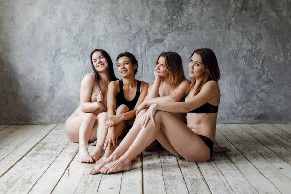 Quatro mulheres multiétnicas em roupa interior posando em cinza, conceito de positividade corporal. Espaço de cópia — Fotografia de Stock