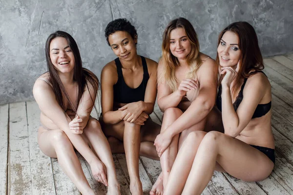 Quatro mulheres multiétnicas em roupa interior posando em cinza, conceito de positividade corporal. Espaço de cópia — Fotografia de Stock