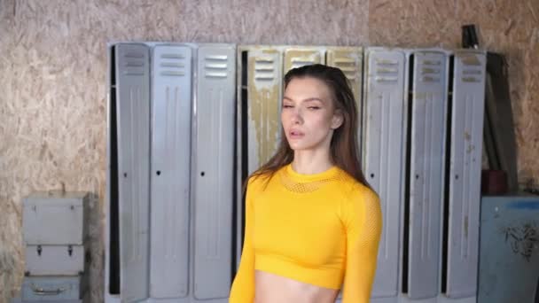 Jovem menina de esportes em um uniforme de esportes amarelo prepare-se para um treino. Academia de estilo loft moderno — Vídeo de Stock