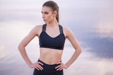  Gün batımında denizin arka planında güzel bir fitness modelinin portresi.