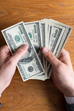 Erkek eller Amerikan dolarlarını sayıyor ya da para geçmişinde nakit ödüyor. Yatırım kavramı, başarı, finansal beklentiler