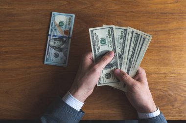 Erkek eller Amerikan dolarlarını sayıyor ya da para geçmişinde nakit ödüyor. Yatırım kavramı, başarı, finansal beklentiler