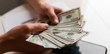 Erkek eller Amerikan dolarlarını sayıyor ya da para geçmişinde nakit ödüyor. Yatırım kavramı, başarı, finansal beklentiler